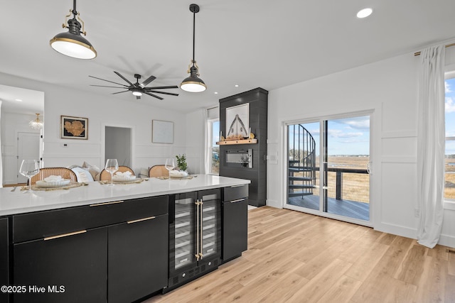 kitchen featuring hanging light fixtures, ceiling fan, wine cooler, and light hardwood / wood-style floors