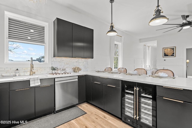 kitchen featuring pendant lighting, dishwasher, beverage cooler, backsplash, and light hardwood / wood-style floors