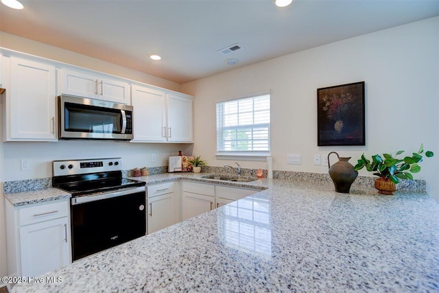 kitchen with sink, light stone countertops, appliances with stainless steel finishes, and white cabinetry