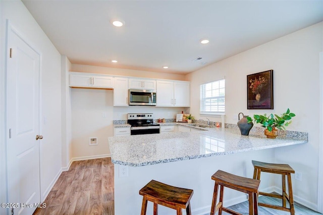 kitchen featuring stainless steel appliances, white cabinetry, and kitchen peninsula