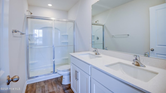 full bath featuring toilet, a stall shower, a sink, and wood finished floors