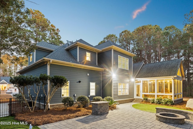 back of property with an outdoor fire pit, a patio, and a sunroom