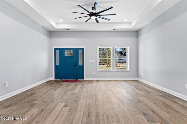 foyer featuring hardwood / wood-style flooring, ceiling fan, and a tray ceiling