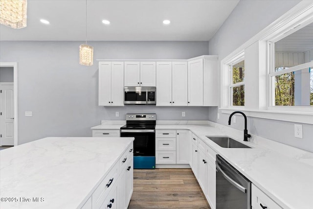 kitchen featuring sink, dark wood-type flooring, hanging light fixtures, stainless steel appliances, and white cabinets