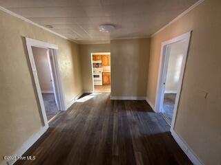 corridor with dark wood-type flooring and ornamental molding