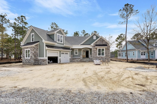 view of front of home featuring a standing seam roof, a shingled roof, a garage, stone siding, and metal roof