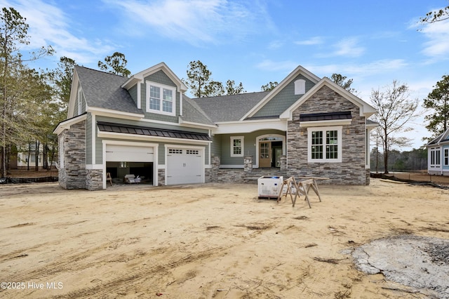 craftsman-style house with stone siding, a garage, and roof with shingles