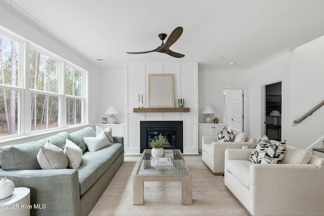 carpeted living room with a large fireplace and ceiling fan