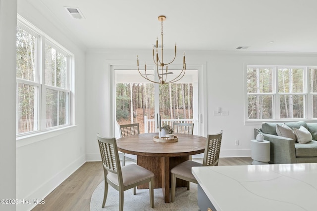 dining area with a healthy amount of sunlight, light hardwood / wood-style flooring, and a chandelier