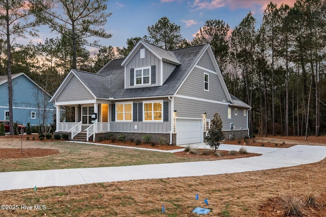 view of front facade featuring covered porch, a yard, and a garage