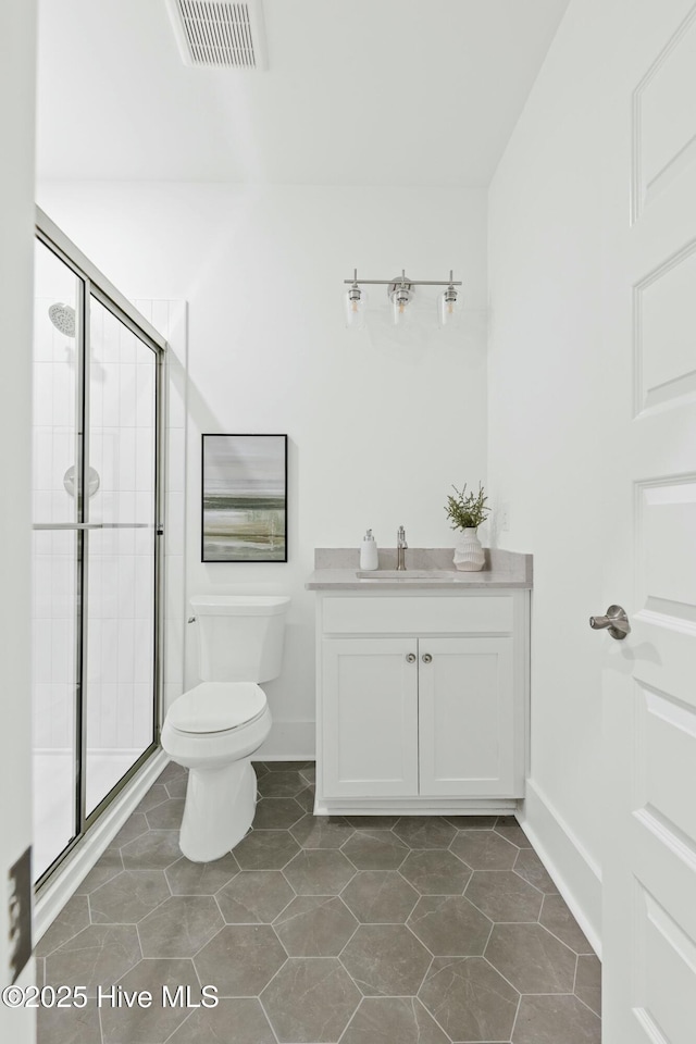 bathroom with a shower with door, tile patterned flooring, vanity, and toilet