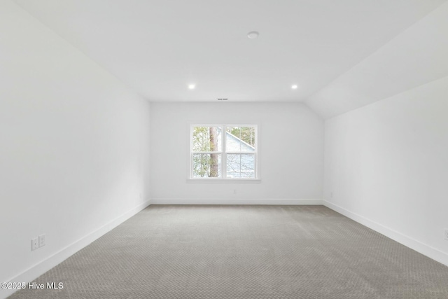 carpeted empty room featuring lofted ceiling