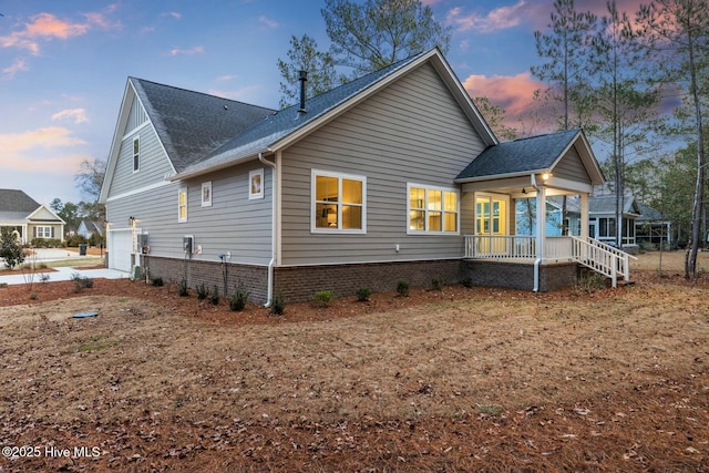 back house at dusk with a porch and a garage