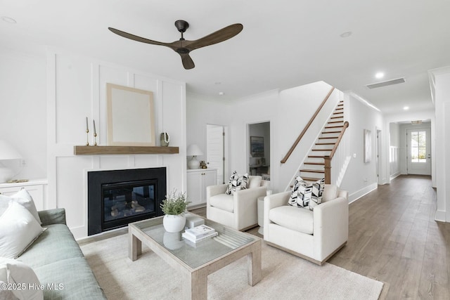 living room featuring ornamental molding, ceiling fan, and light wood-type flooring