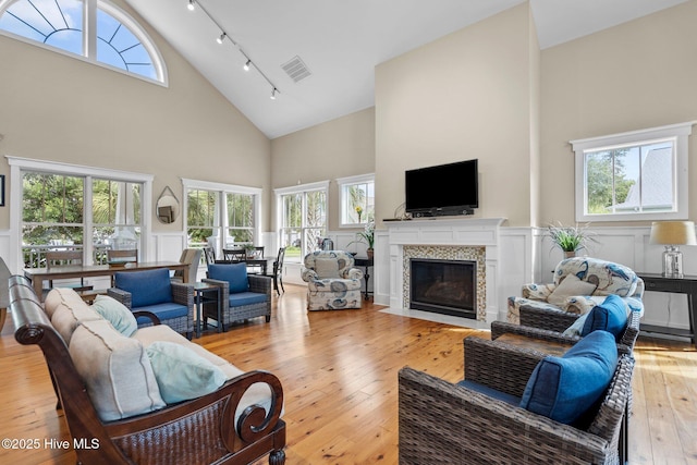 living room featuring hardwood / wood-style flooring, a fireplace, visible vents, a healthy amount of sunlight, and track lighting