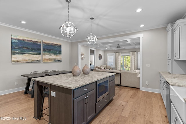 kitchen featuring stainless steel appliances, coffered ceiling, crown molding, and light wood finished floors