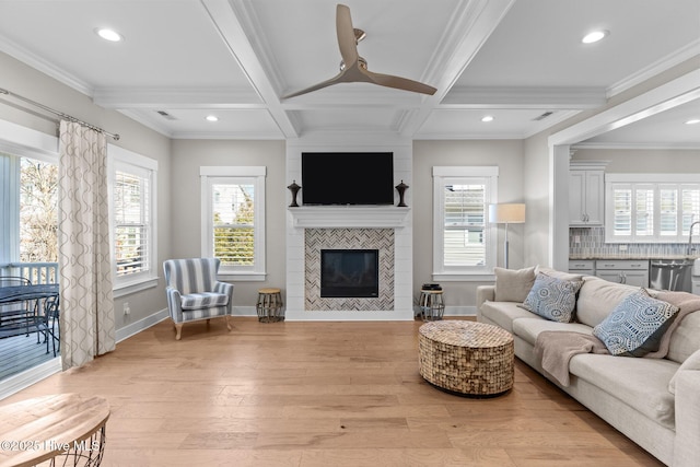 living area featuring coffered ceiling, baseboards, light wood finished floors, beamed ceiling, and a tiled fireplace