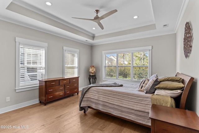 bedroom featuring a tray ceiling, visible vents, light wood-style flooring, and baseboards