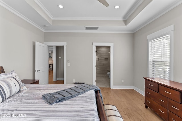 bedroom with light wood finished floors, visible vents, a raised ceiling, and ornamental molding