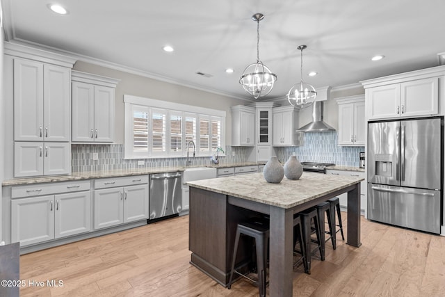 kitchen with visible vents, ornamental molding, stainless steel appliances, wall chimney range hood, and a kitchen bar