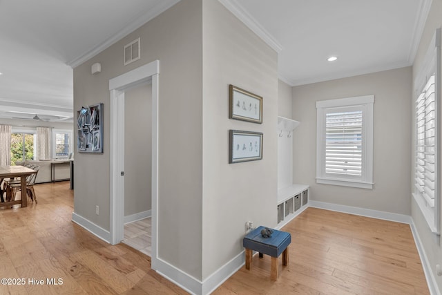 hall featuring ornamental molding, visible vents, light wood-style floors, and baseboards