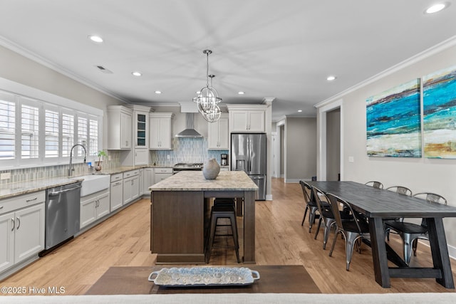 kitchen with appliances with stainless steel finishes, crown molding, a sink, and wall chimney exhaust hood