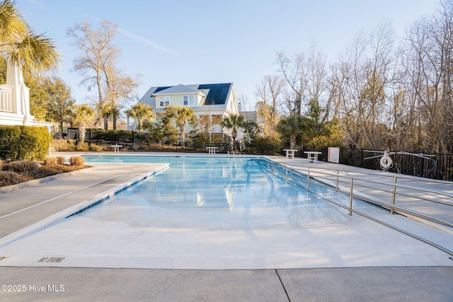 community pool with a patio area and fence