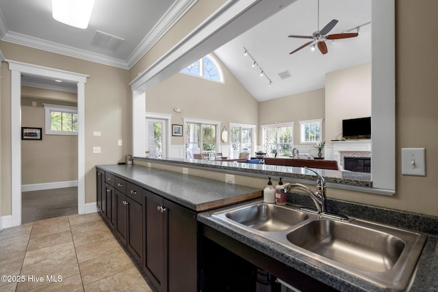 kitchen with dark countertops, visible vents, a ceiling fan, a sink, and open floor plan