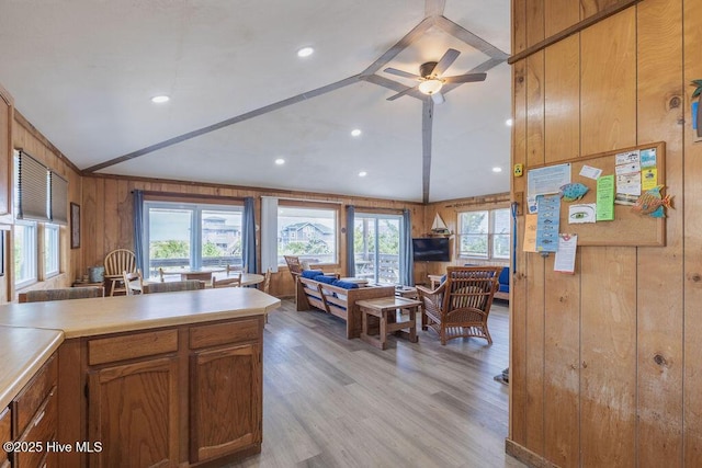 kitchen with ceiling fan, lofted ceiling, wooden walls, and light hardwood / wood-style flooring