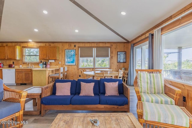 living room featuring sink, light wood-type flooring, wood walls, and vaulted ceiling