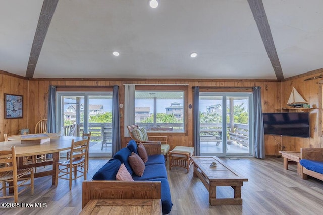 living room with light hardwood / wood-style floors, beam ceiling, and wooden walls