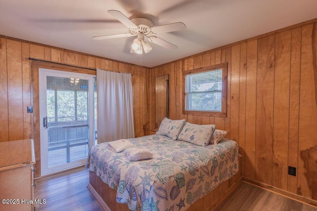 bedroom with ceiling fan, multiple windows, and wooden walls