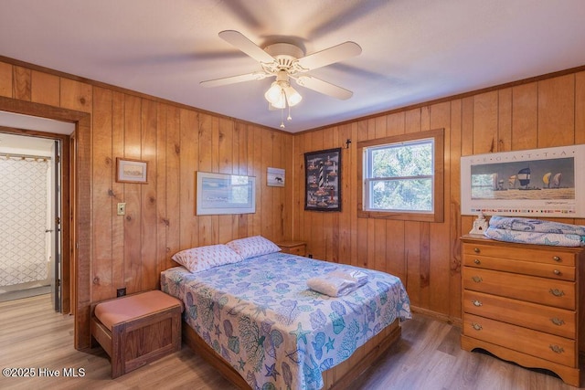 bedroom with ceiling fan, wood-type flooring, and wooden walls