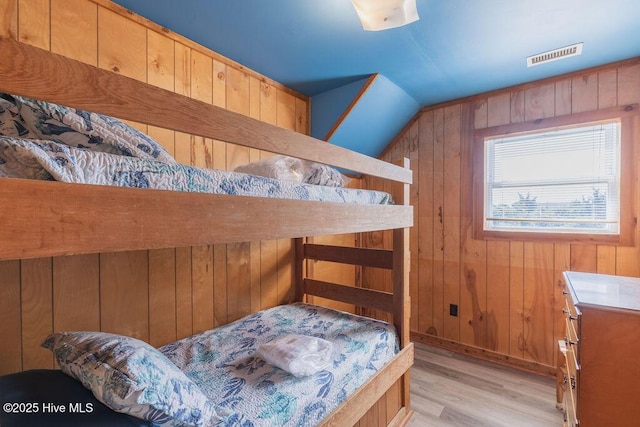 bedroom featuring light wood-type flooring and wooden walls