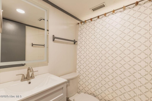 bathroom featuring toilet, vanity, and walk in shower