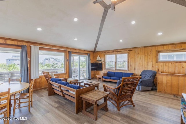 living room featuring ceiling fan, light hardwood / wood-style floors, and wooden walls