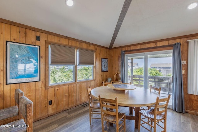 dining area featuring wood walls, hardwood / wood-style floors, and beam ceiling