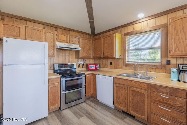 kitchen with wood walls, white appliances, light wood-type flooring, beam ceiling, and sink