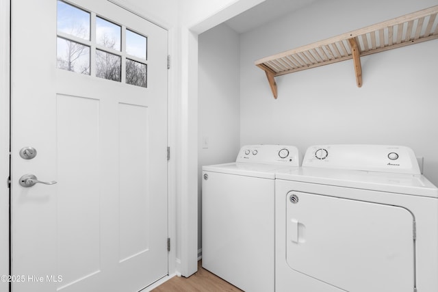 clothes washing area with light wood-type flooring and separate washer and dryer