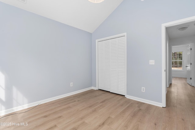 unfurnished bedroom with lofted ceiling, a closet, and light hardwood / wood-style flooring