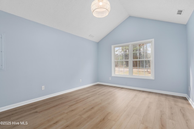 empty room featuring light wood-type flooring and vaulted ceiling