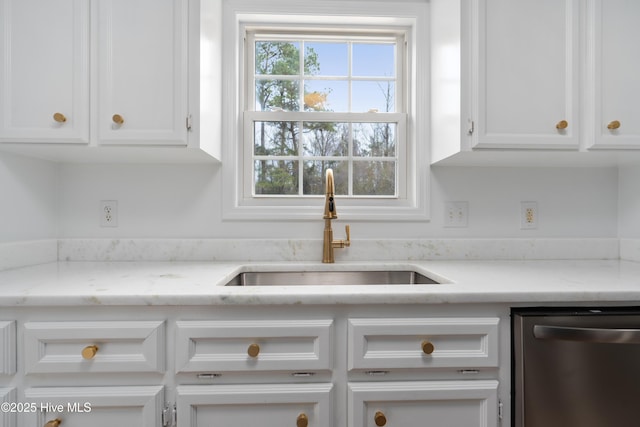 kitchen with light stone counters, white cabinets, stainless steel dishwasher, and sink