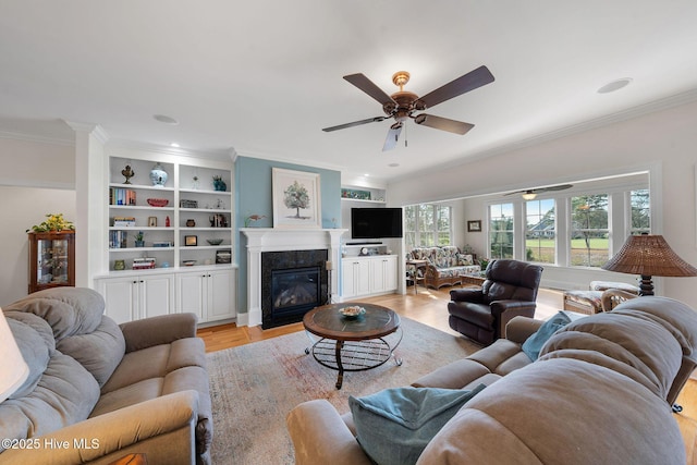 living room featuring ceiling fan, crown molding, and light hardwood / wood-style flooring