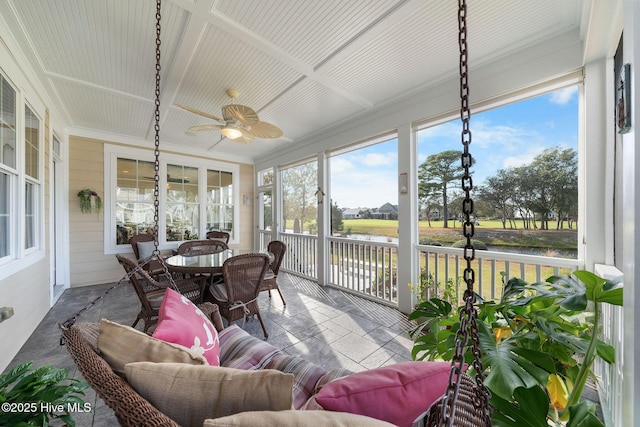 sunroom featuring ceiling fan and a water view