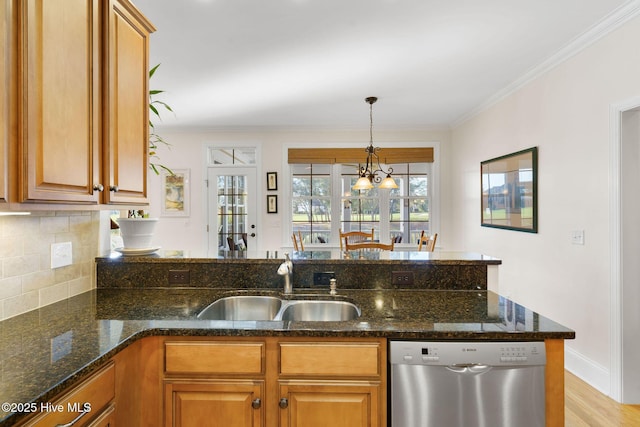 kitchen with a chandelier, stainless steel dishwasher, dark stone counters, and sink