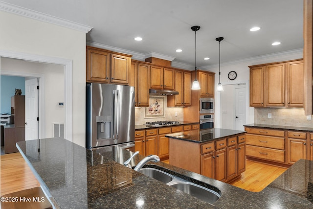 kitchen with pendant lighting, a kitchen island, stainless steel appliances, sink, and backsplash