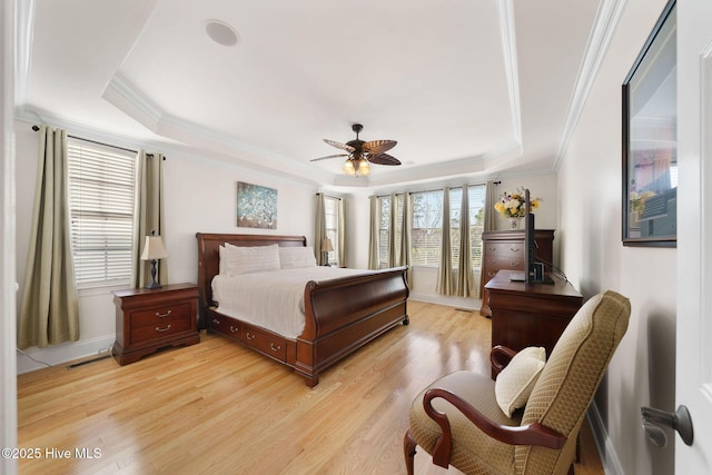 bedroom featuring ceiling fan, ornamental molding, light hardwood / wood-style flooring, and a raised ceiling