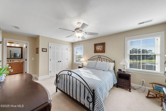 bedroom featuring ceiling fan, light colored carpet, a closet, and connected bathroom