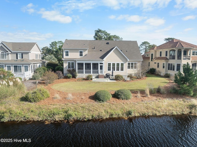 rear view of property with a sunroom, a water view, and a lawn