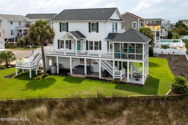 back of house featuring a lawn, a hot tub, a patio, and a sunroom